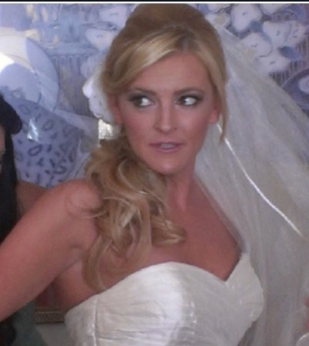 Woman with blonde hair in a wedding dress and veil, looking to the side, in a close-up shot.