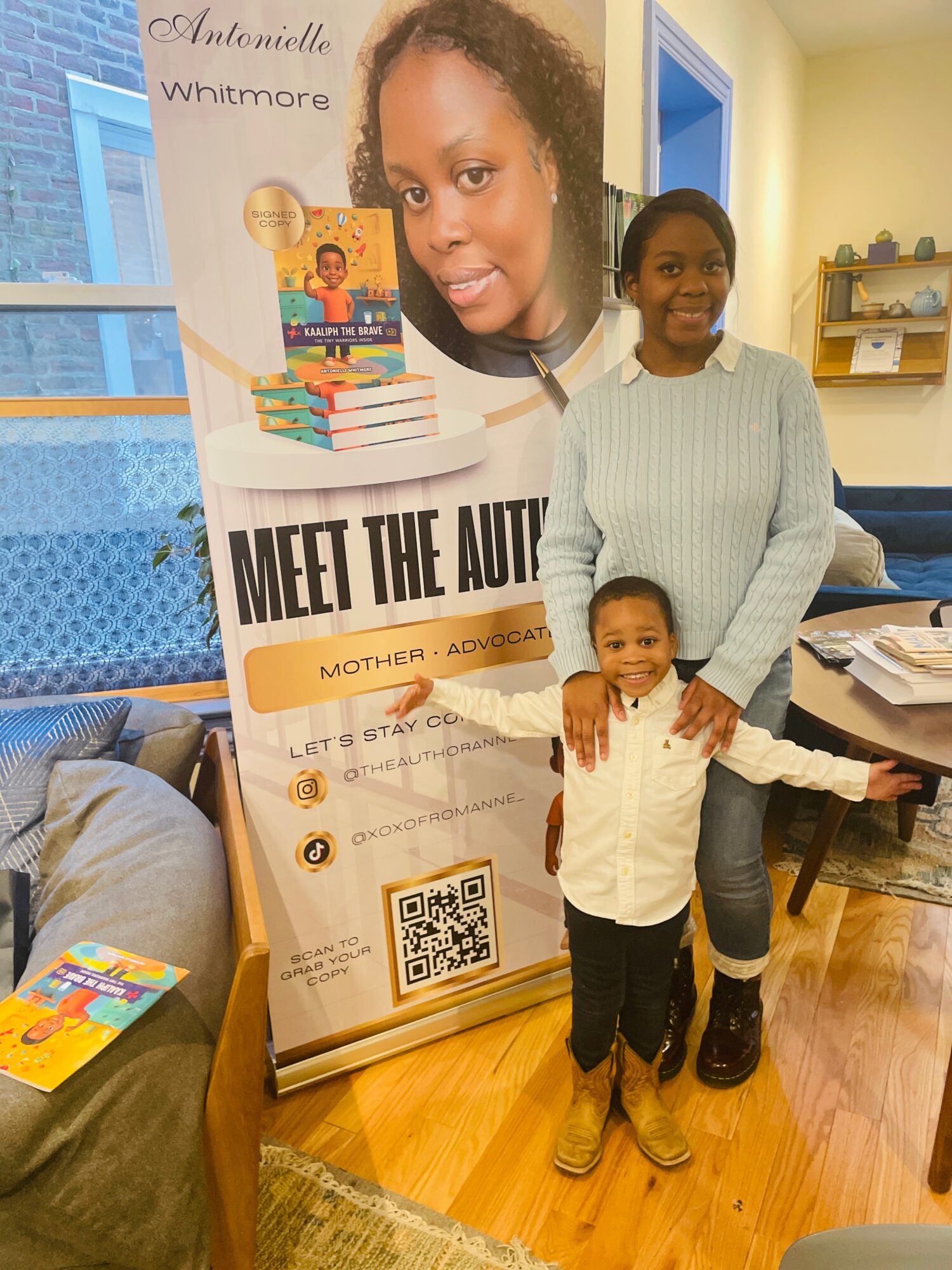 A woman and two children stand indoors next to a large poster with a woman's face and text about autism awareness.
