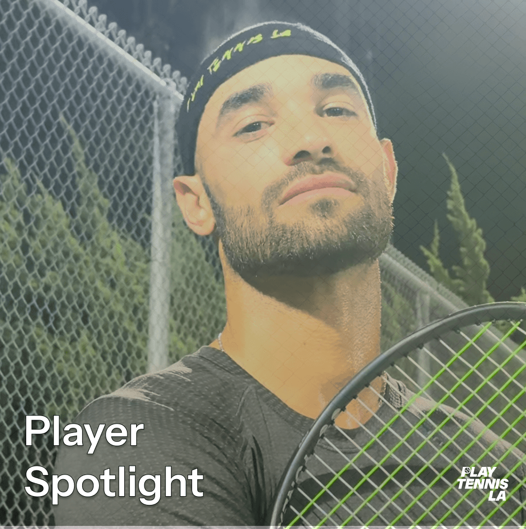 Male tennis player with a headband, holding a tennis racket, outdoors at night, fence and trees in background.
