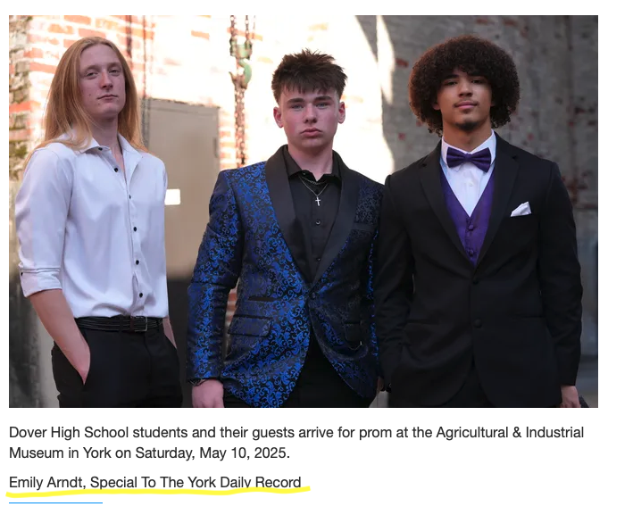 Three young men in formal attire standing outdoors, with a brick wall background.