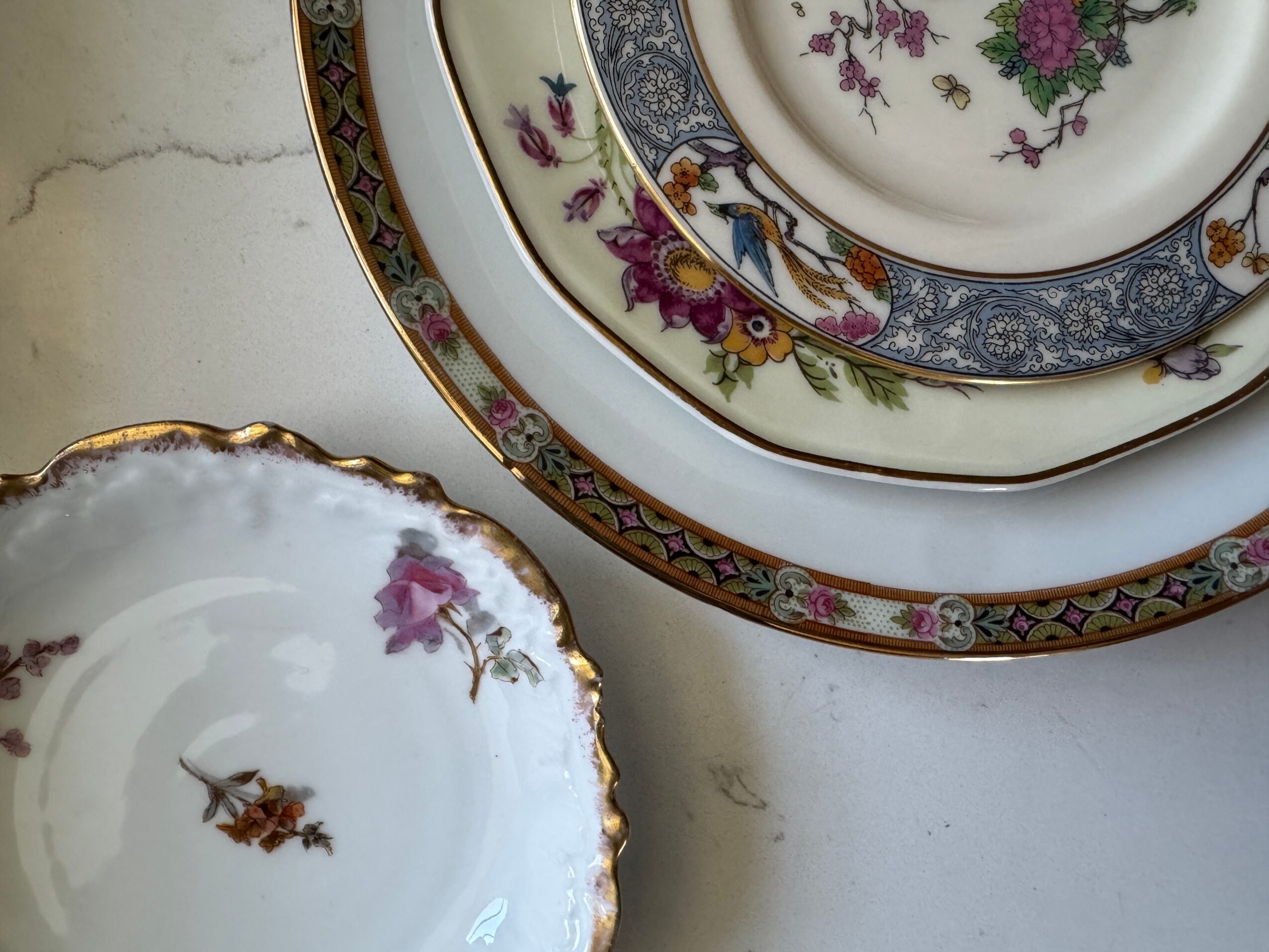 Three decorative plates with floral and ornate patterns stacked on a white surface.