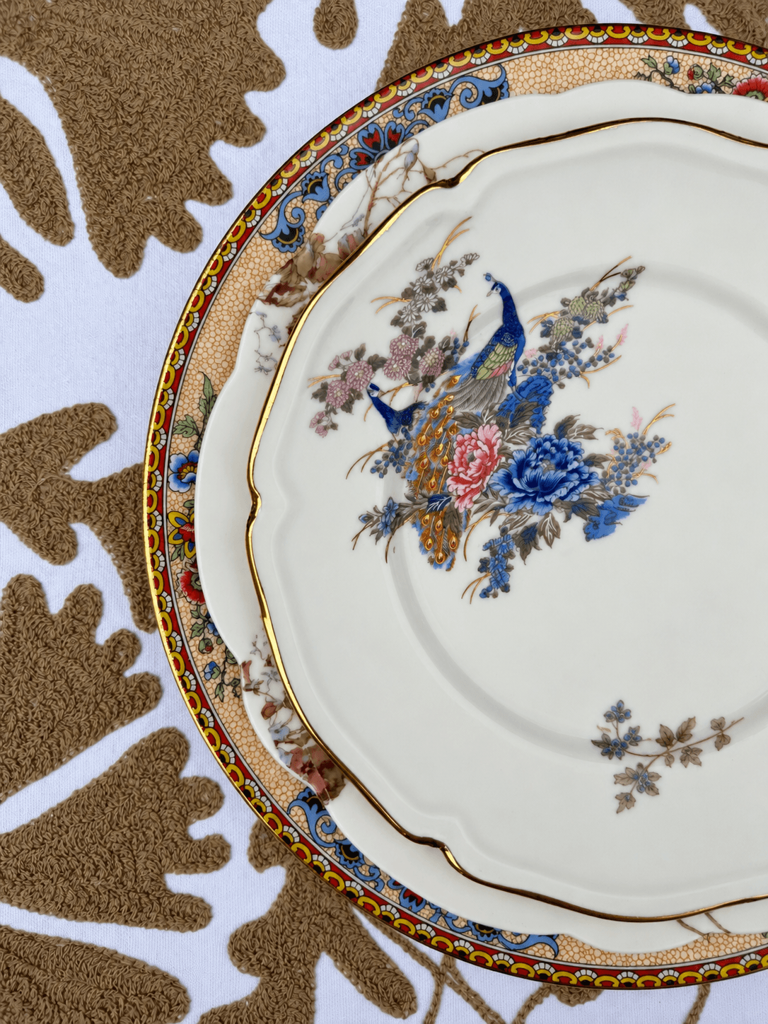Decorative floral plates stacked on a patterned surface, featuring intricate designs and colorful flowers.