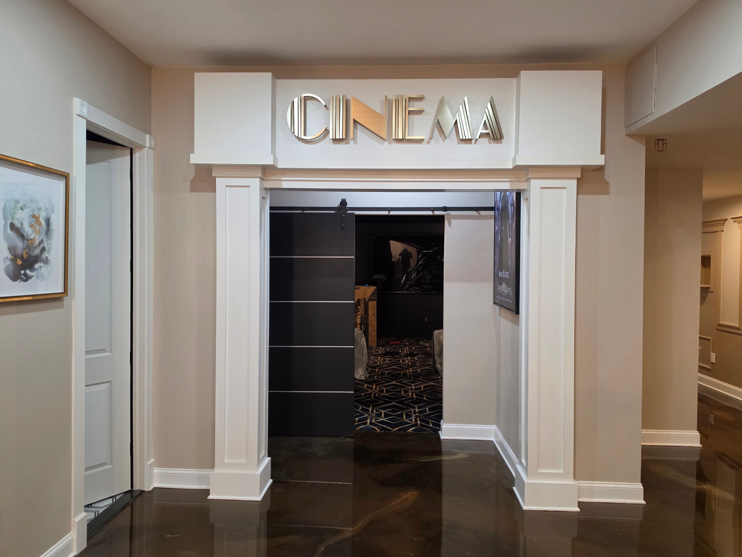 Entrance to a cinema with a sign above reading 'CINEMA', white columns, and a dark interior visible through the doorway.