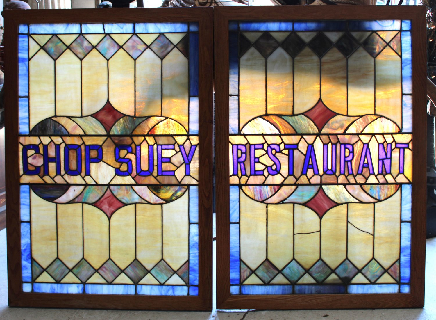 Stained glass window with text 'Chop Suey Restaurant' in purple, decorative geometric patterns, and colorful glass.