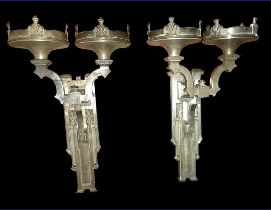 Two ornate metal lamp posts with multiple candle holders against a black background.