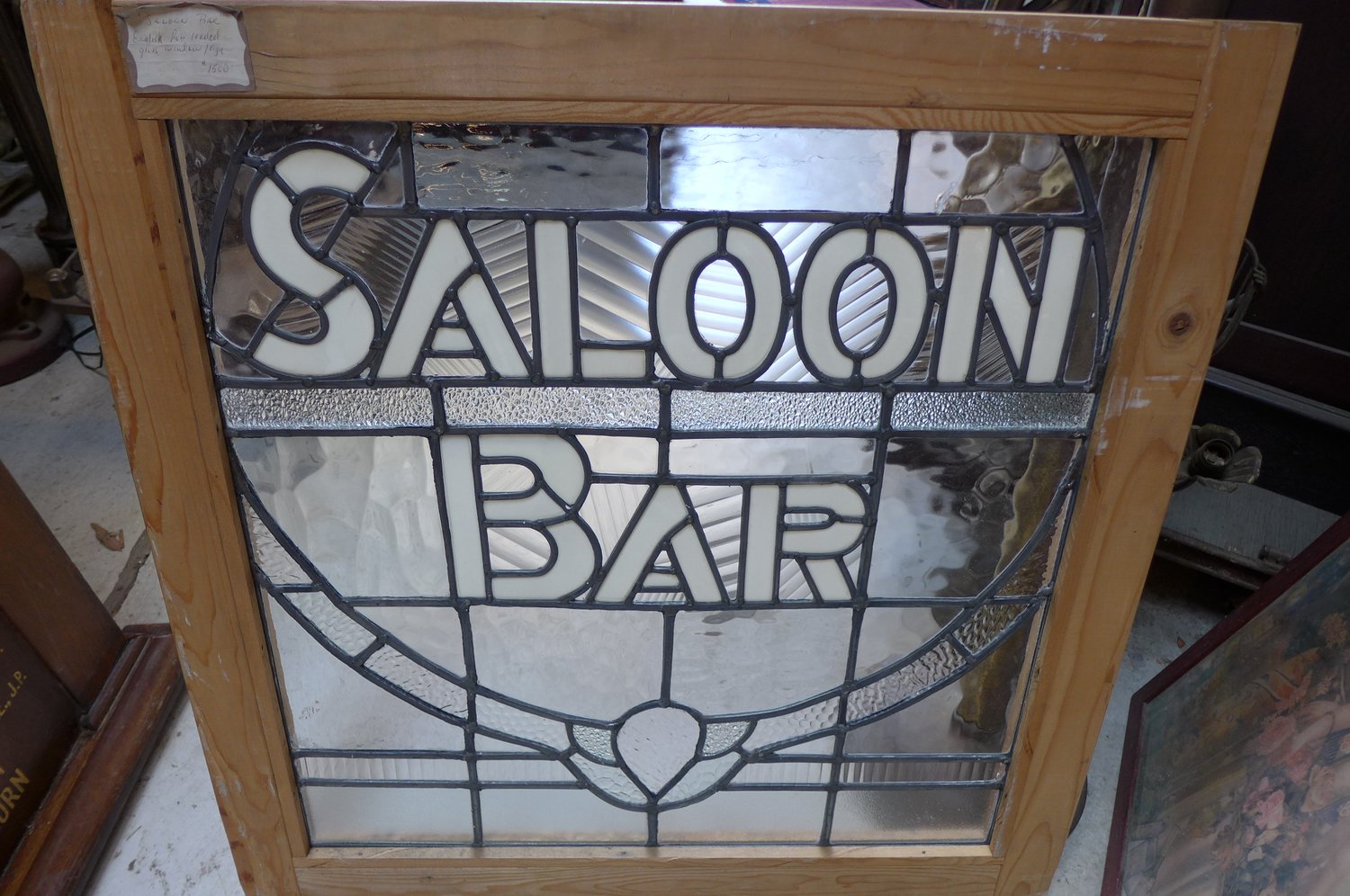 Decorative glass window with the words 'Saloon' and 'Bar' in black and white, framed in wood.