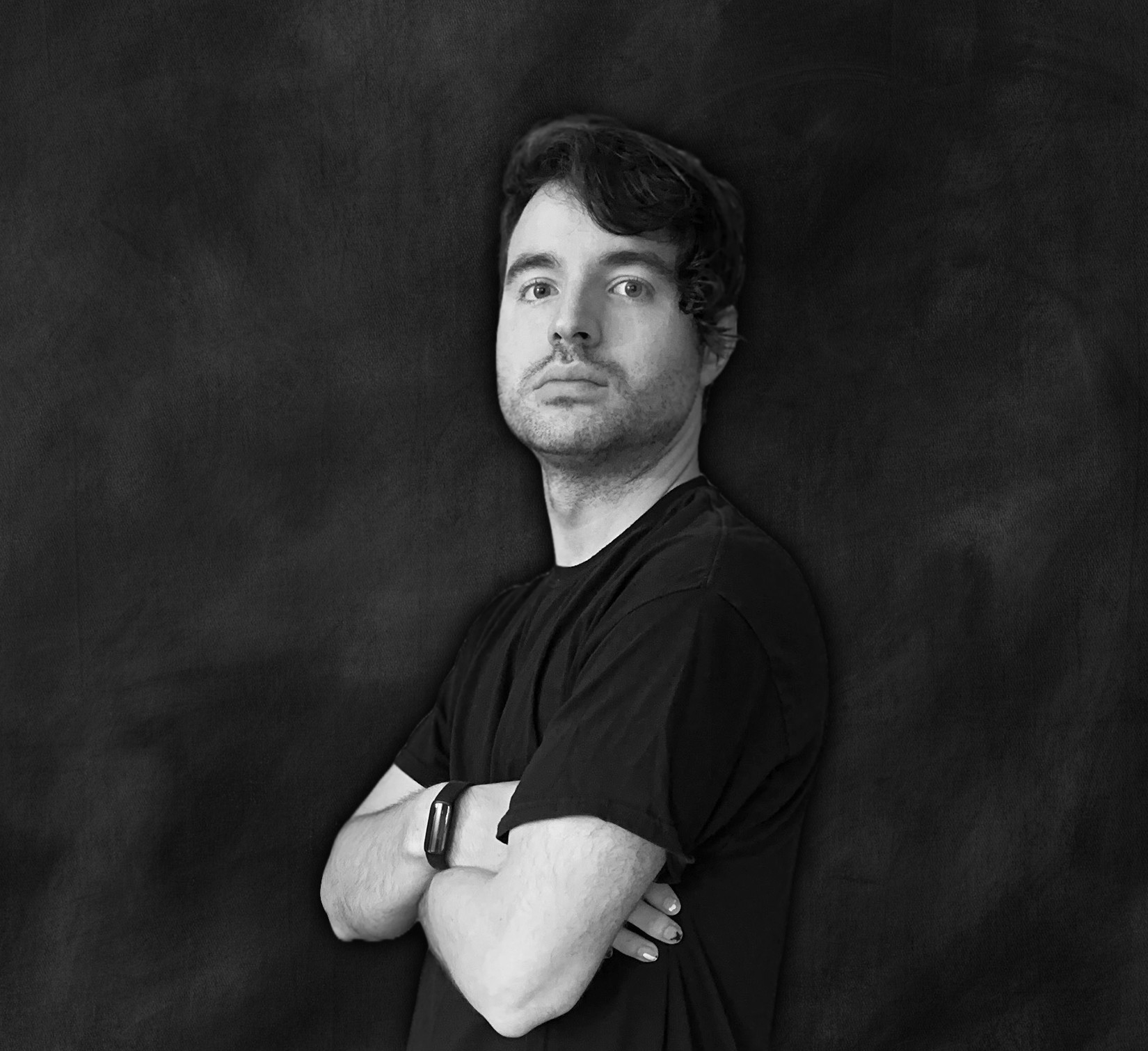 Portrait of a man with crossed arms, looking at the camera, against a dark background.