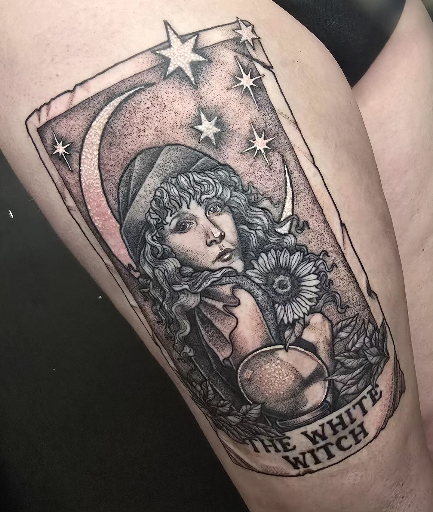 Tattoo of a woman with curly hair, surrounded by stars, a crescent moon, and a crystal ball, with the text 'The White Witch'.