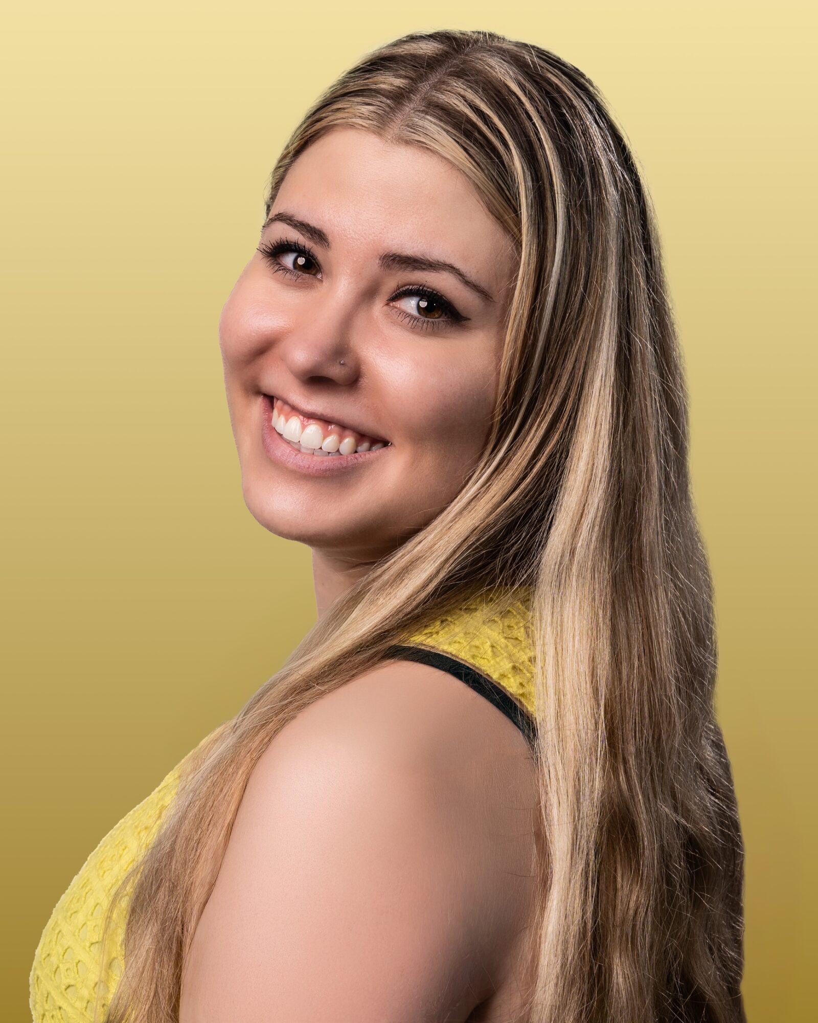 Young woman with long blonde hair smiling, wearing a yellow top, against a light yellow background.