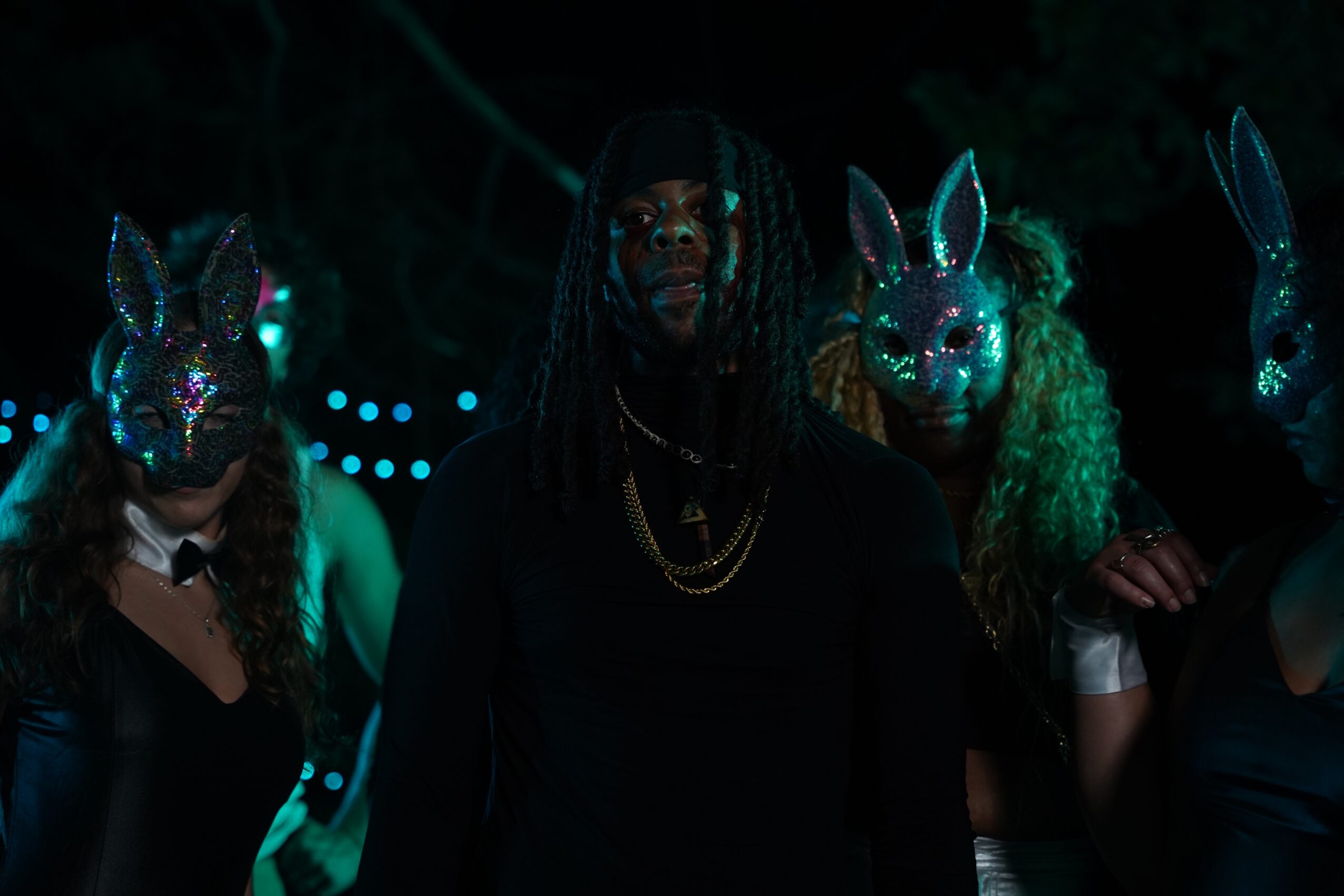 Group of people wearing illuminated animal masks, dark background, colorful lighting, party or event setting.