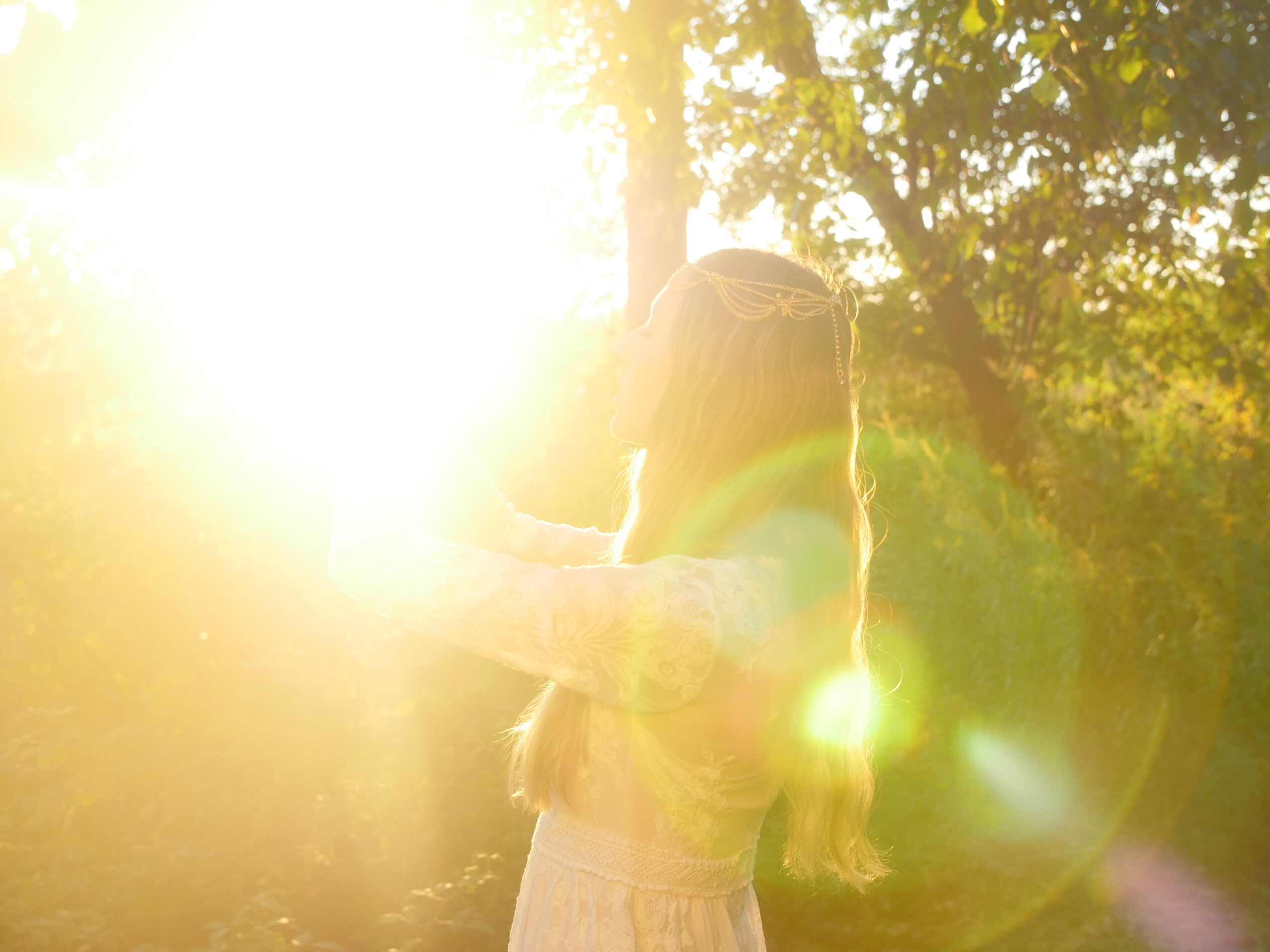 Two people embrace outdoors with sunlight shining brightly behind them, creating lens flare and backlighting.