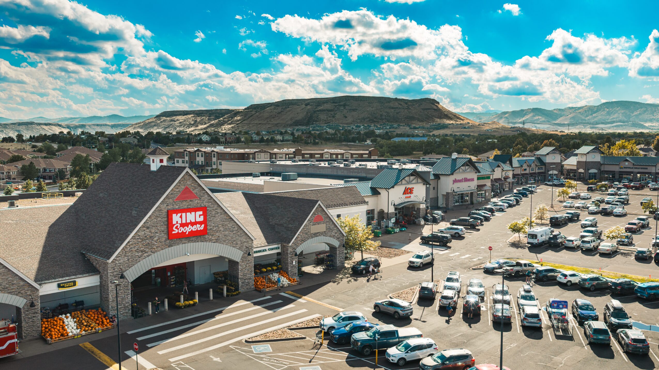 King Superstore with parking lot and cars, hills and blue sky with clouds in background.