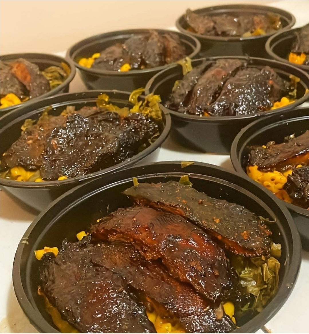 Multiple black bowls filled with cooked meat and yellow rice, arranged on a white surface.