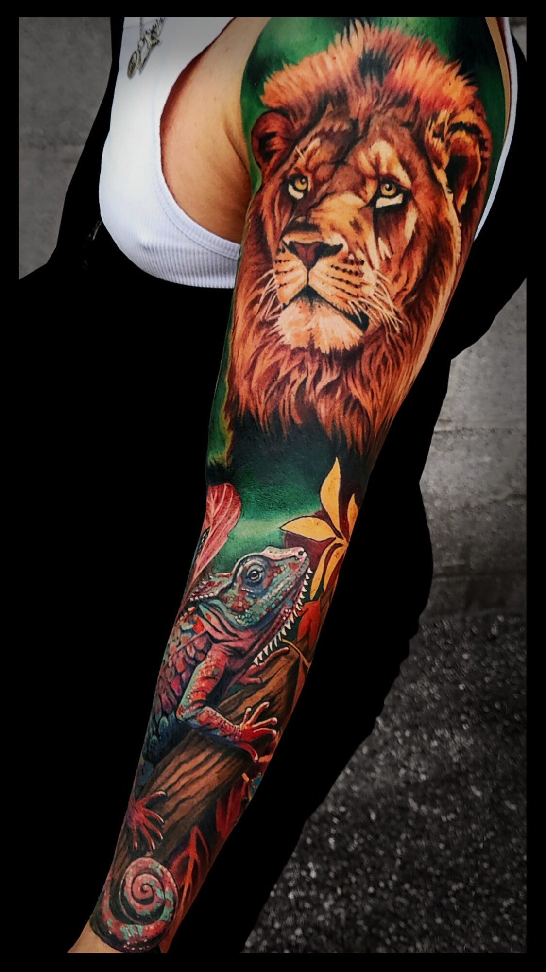 Tattoo of a lion's face on a person's arm with colorful background and detailed design.