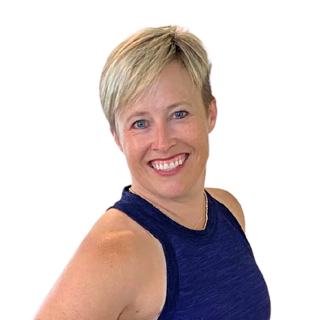Woman with short blonde hair smiling, wearing a sleeveless dark blue top, against a black background.