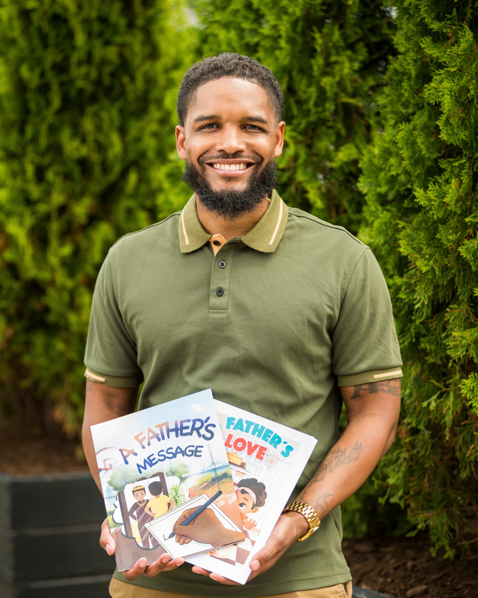 Smiling man holding colorful cards outdoors with green foliage background.