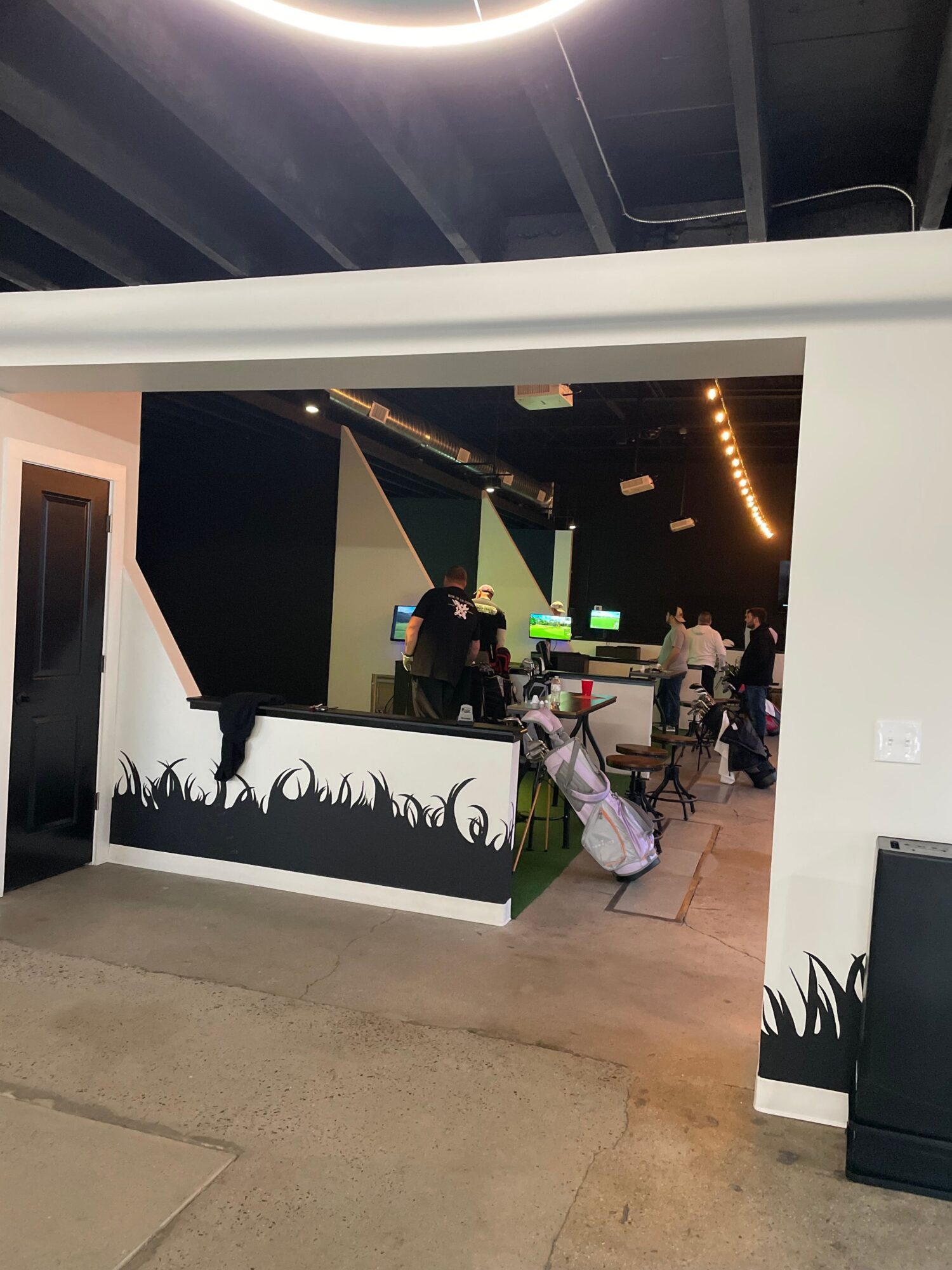 People sitting at a counter with a black and white decorative front, in a modern indoor space.