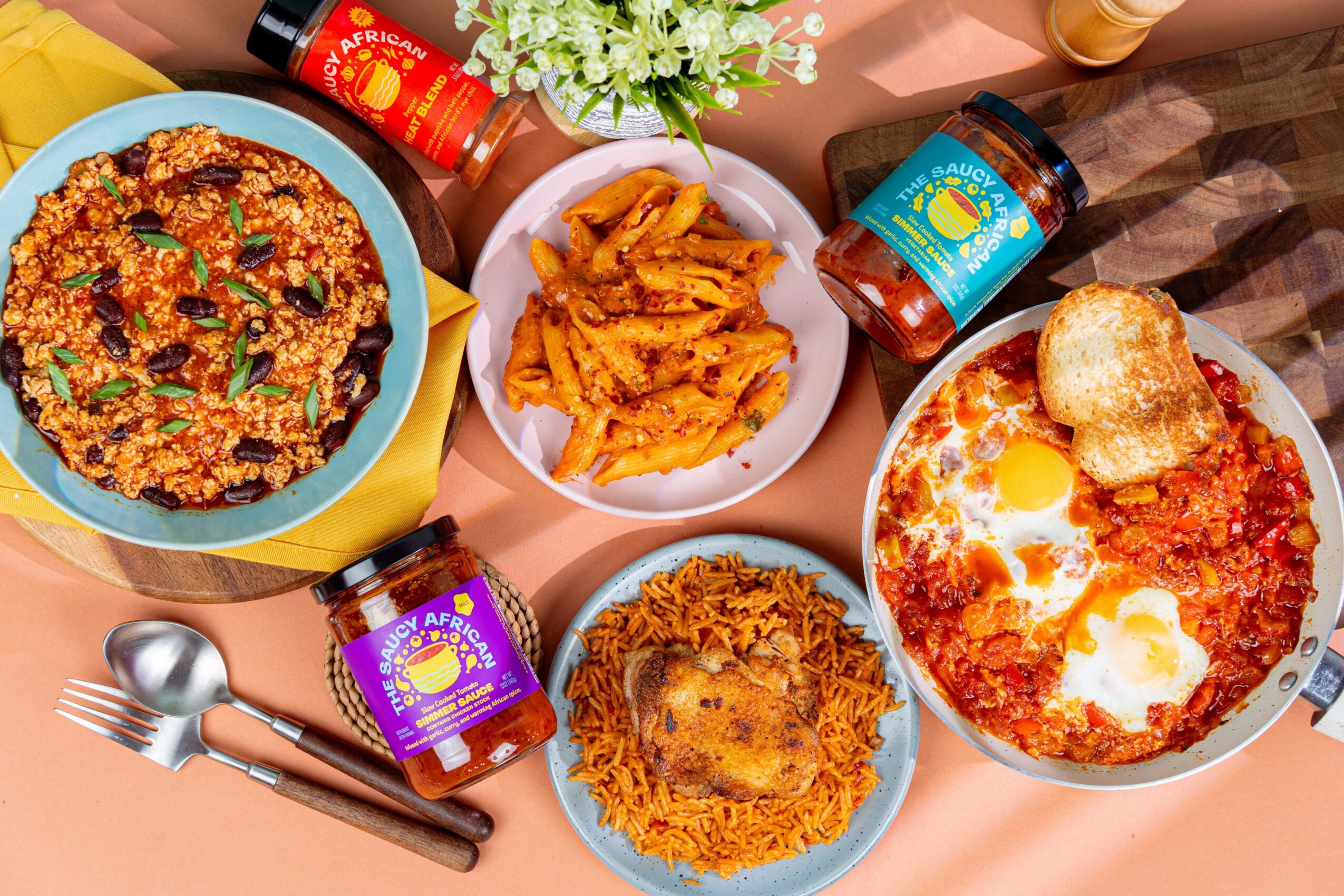 Pizza, fried chicken, pasta, and a dish with eggs on a table with condiments and flowers