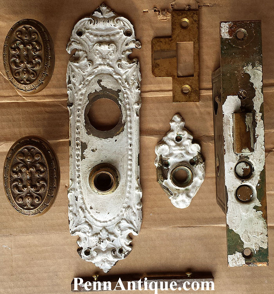Collection of antique metal and decorative objects on a wooden surface, including ornate plates and hardware pieces.