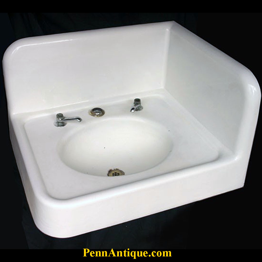 White vintage sink with two faucet holes and an oval basin, against a dark background.