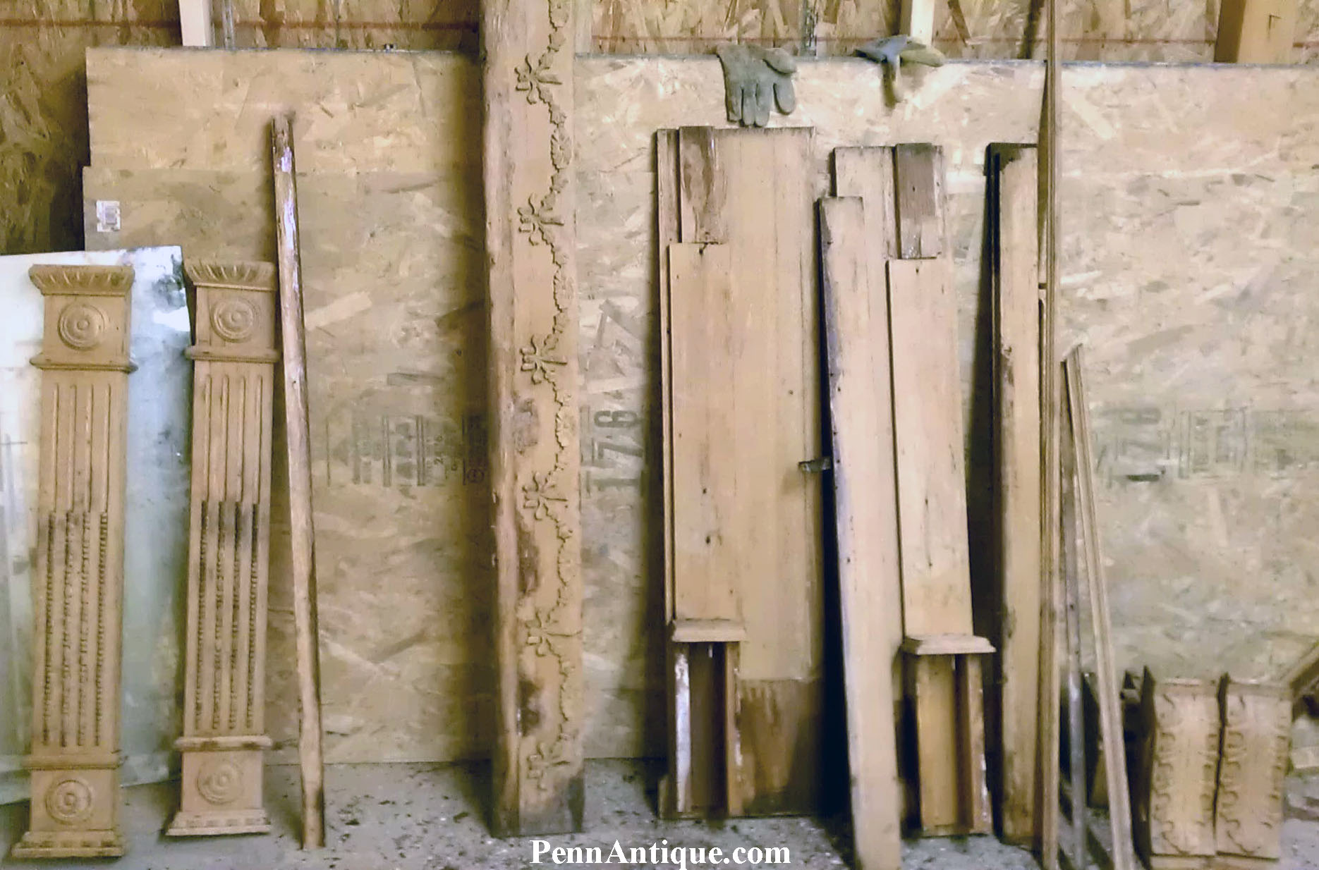 Wooden and decorative columns leaning against a wall in a workshop or storage area.