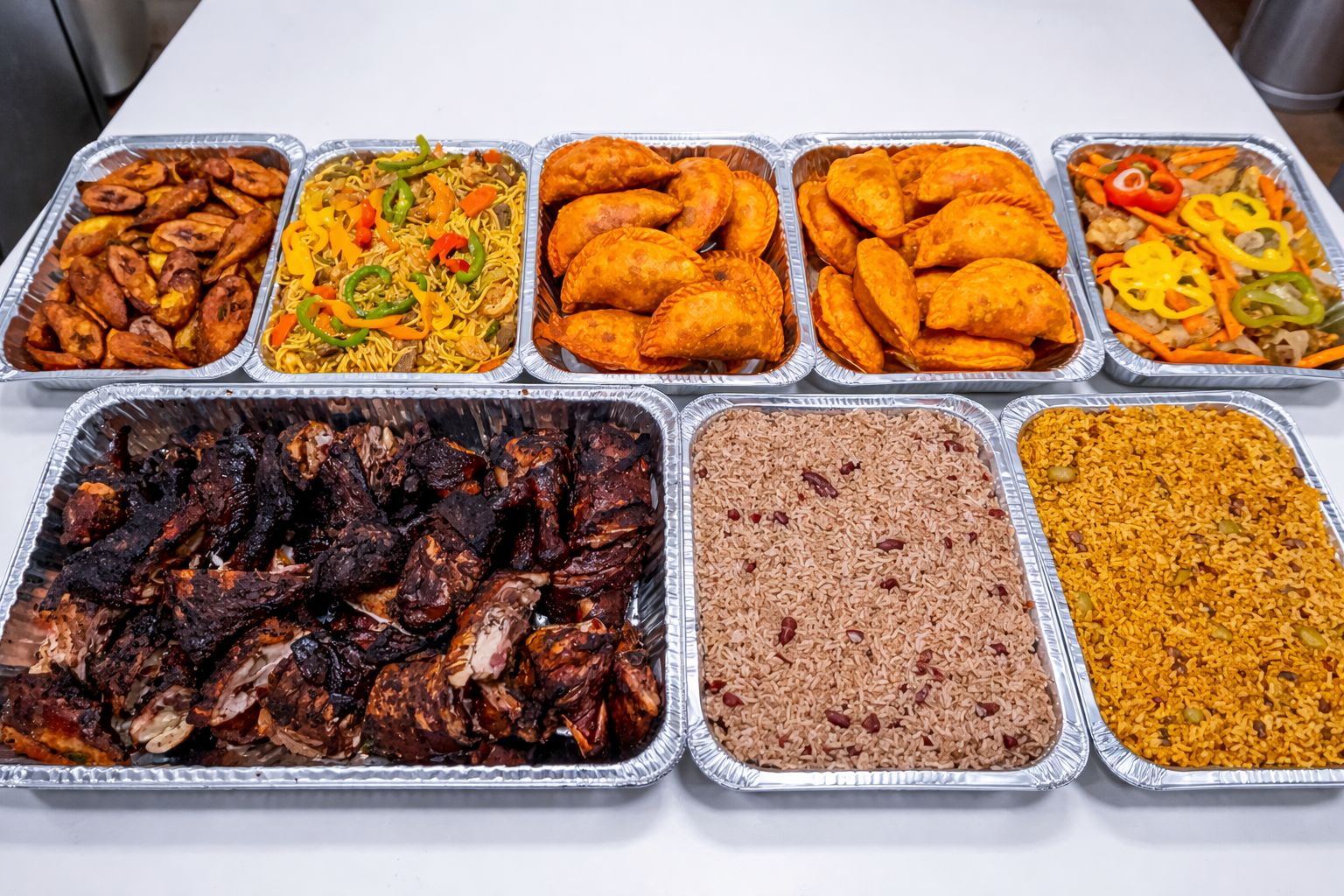 Tray of grilled meat, rice, fried chicken, chicken nuggets, mixed vegetables, and seasoned rice dishes, arranged on a table.
