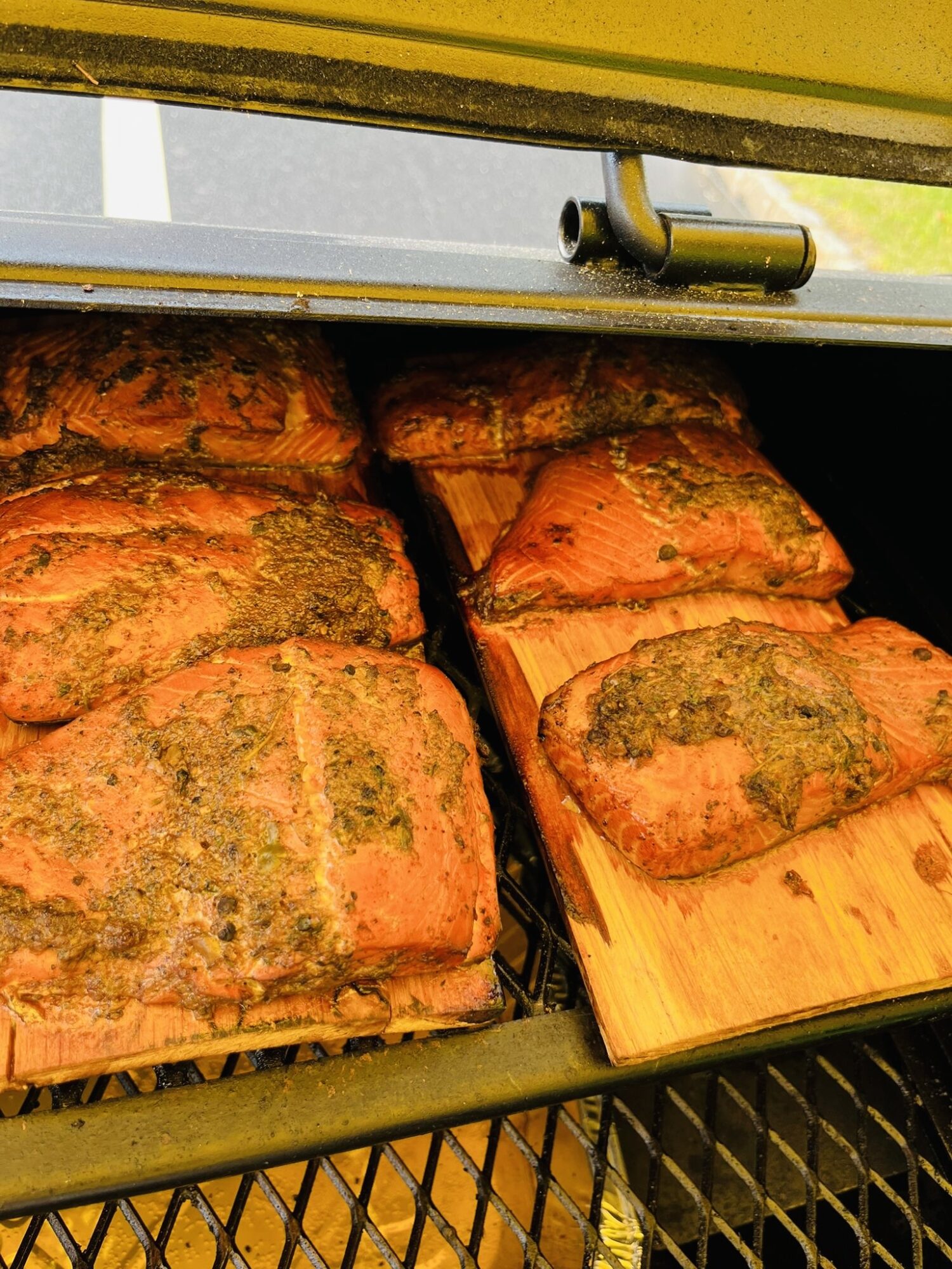 Several seasoned meatloaves on a wooden board inside an oven, with a metal latch visible at the top.