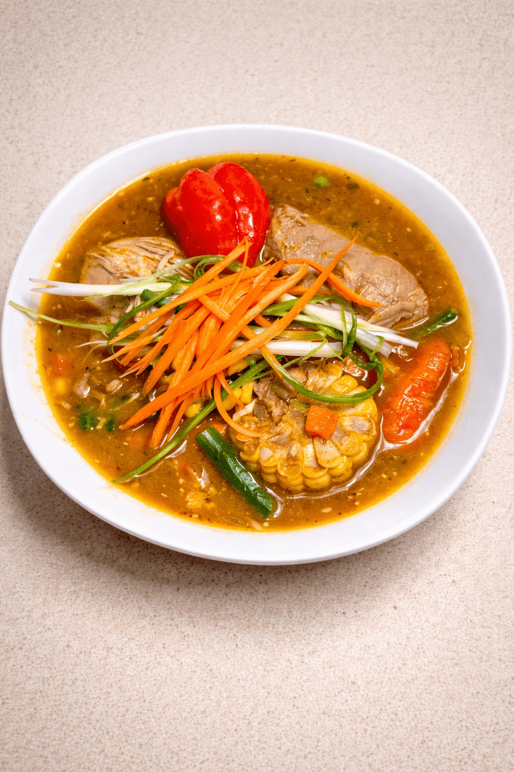 Bowl of vegetable and meat soup with tomato, carrots, corn, and green beans in broth, on a beige surface.