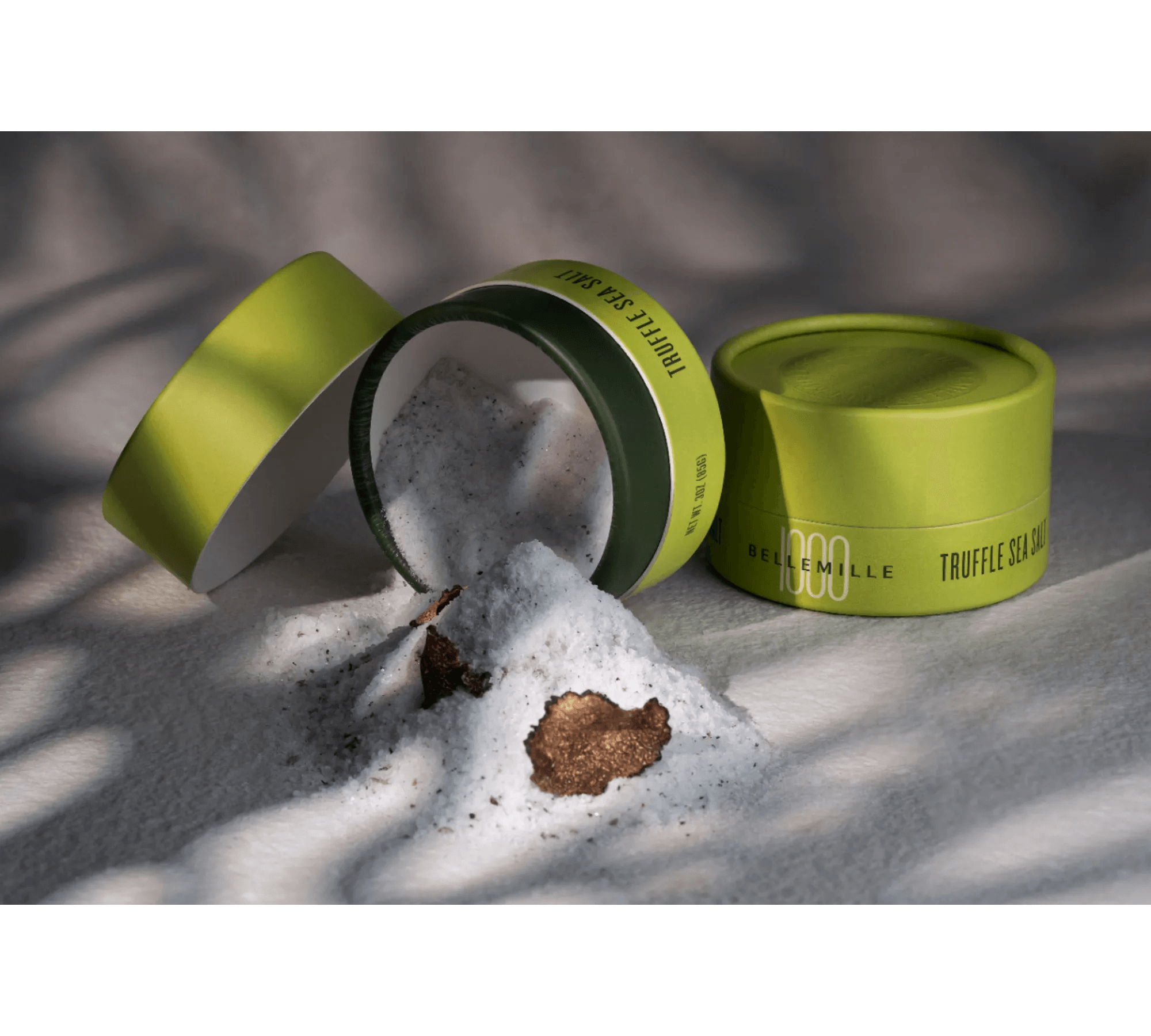 Three green cylindrical containers with foam spilling out, on a gray surface with a blurred background.