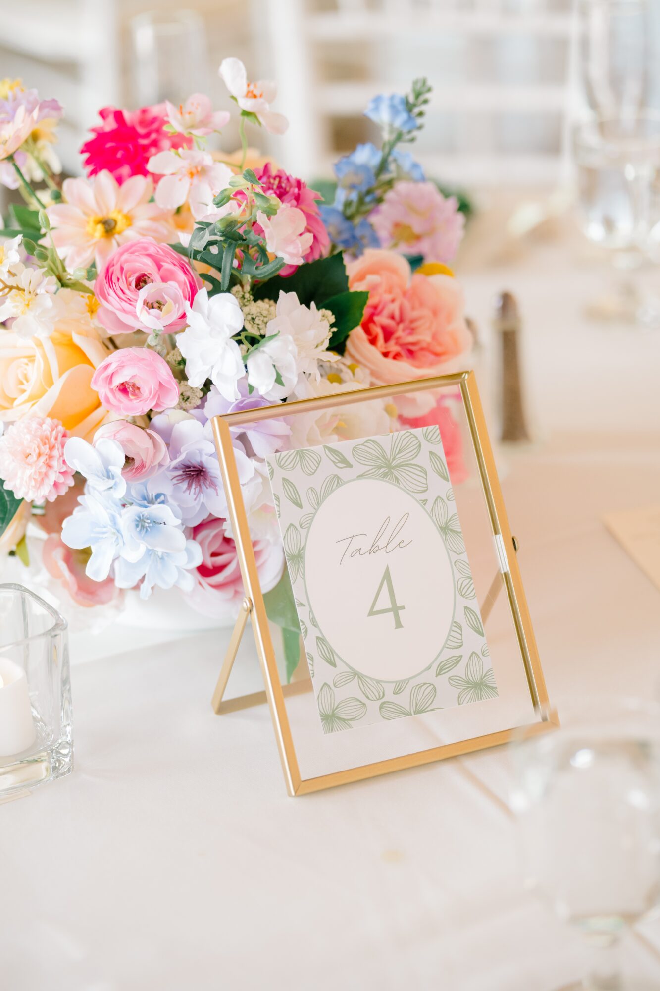 Table number 4 sign with floral design, surrounded by colorful flower arrangements, on a table at an event.