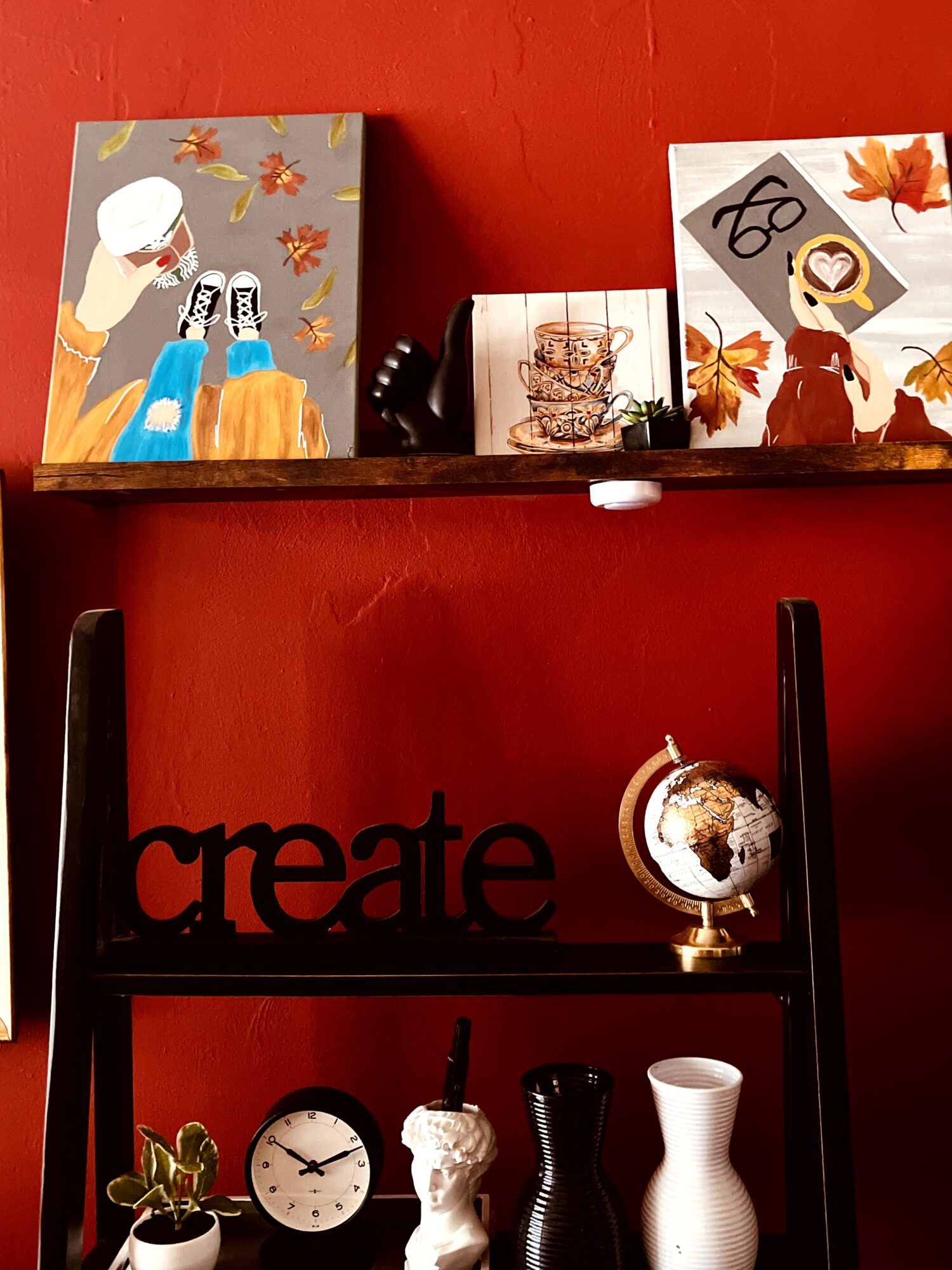 Shelf with three decorative boxes, a small globe, and a black word sign reading 'create' against a red wall.
