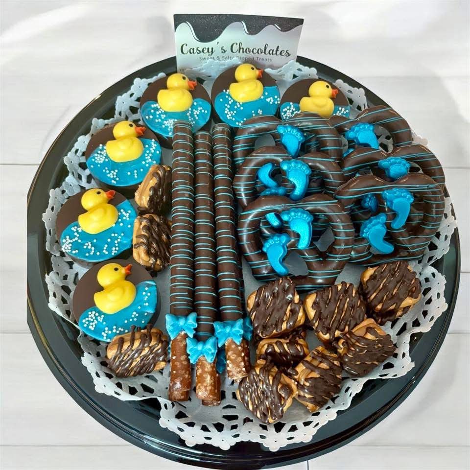 Assorted chocolate treats with blue and yellow decorations on a black tray, with a label reading 'Casey's Chocolates'.