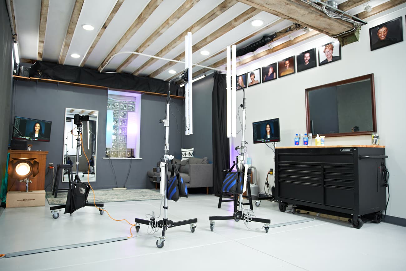 A modern hair salon with styling chairs, mirrors, and hair products, featuring a white floor and exposed ceiling beams.