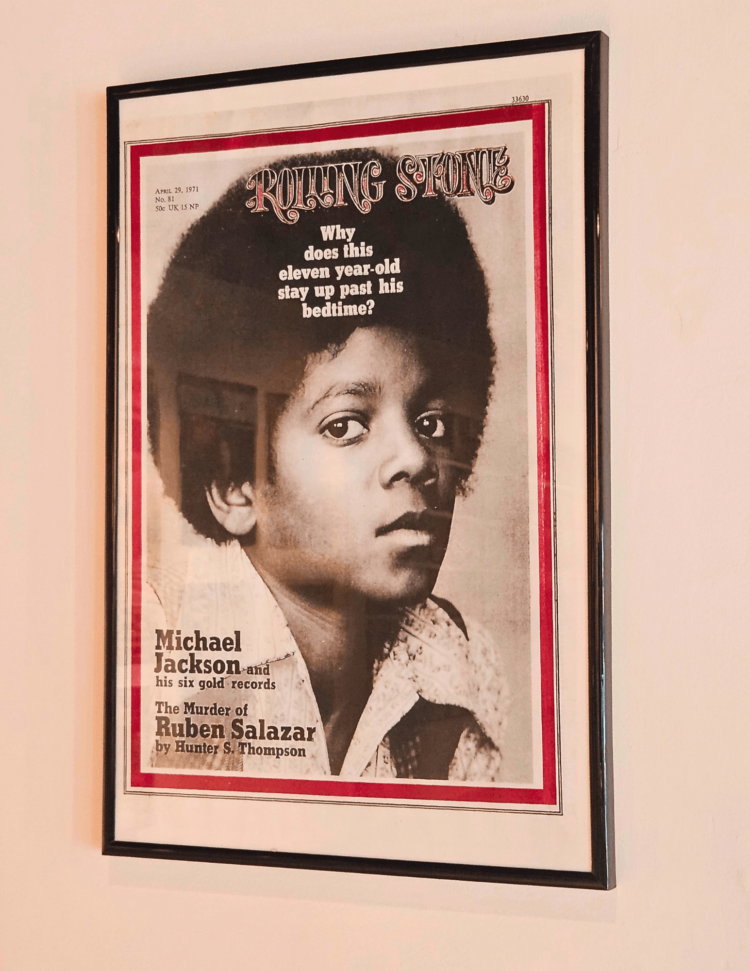 Framed poster of a young boy with short hair, featuring a Rolling Stone magazine cover design, hanging on a wall.