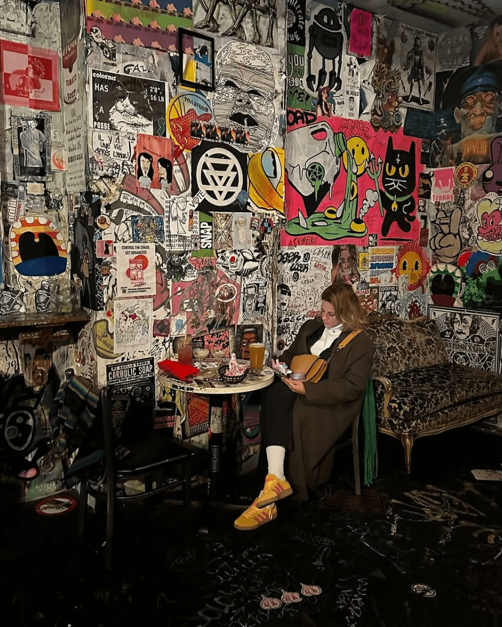 Person sitting at a table with a laptop in a room decorated with colorful graffiti and artwork on the walls.