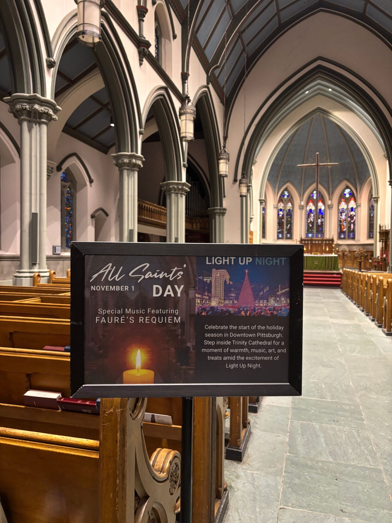 Interior of a church with an electronic display board, ornate architecture, and a view toward the altar.