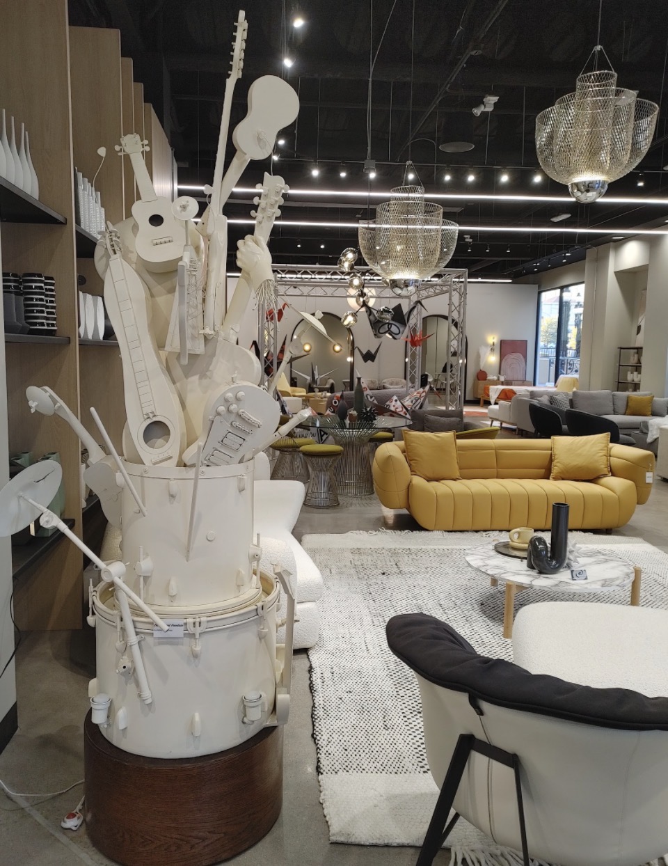 Interior of a furniture store with yellow sofas, decorative lighting, and a white sculpture in the foreground.