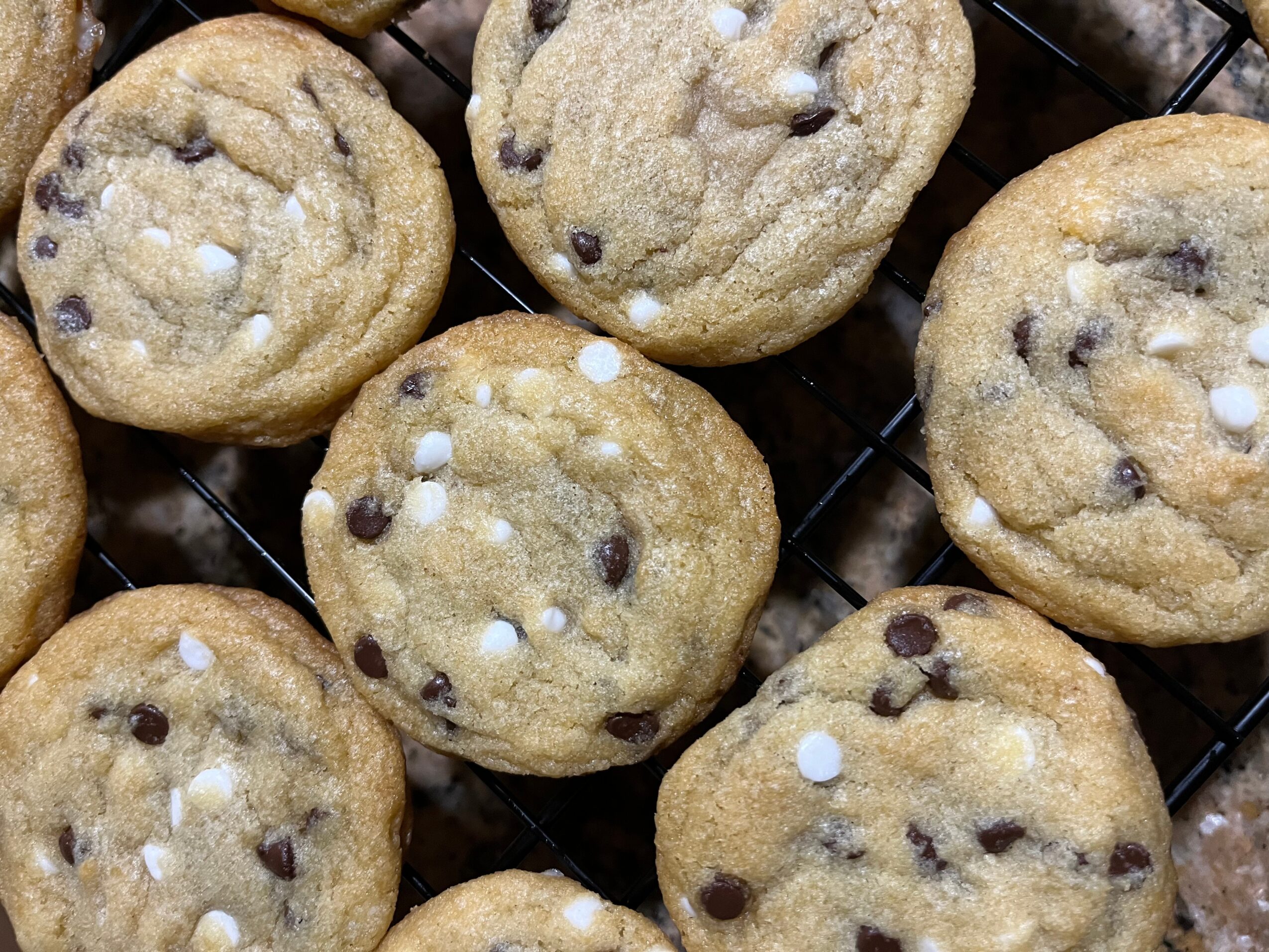 Close-up of chocolate chip cookies with white chocolate chips on a cooling rack.
