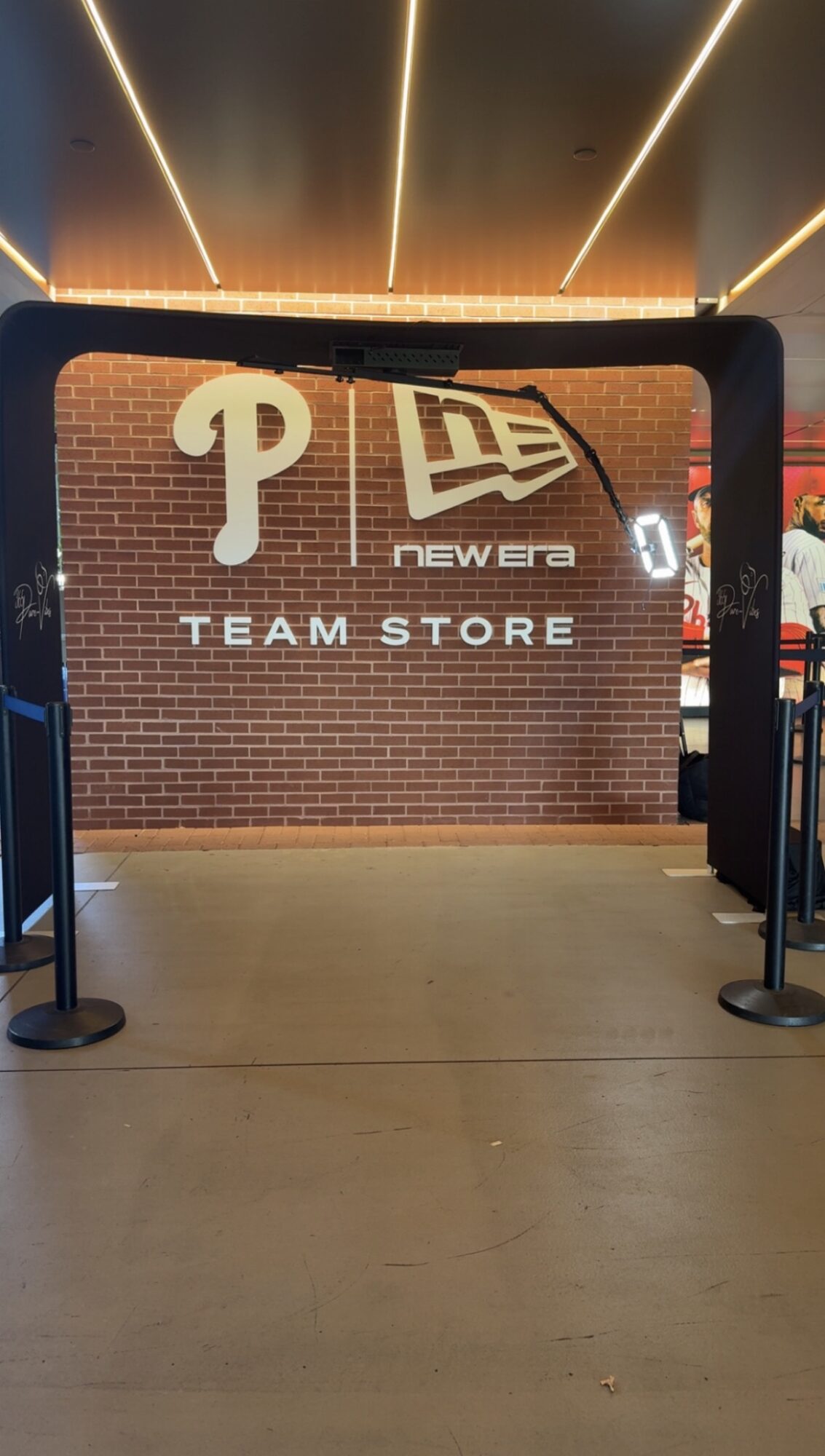 Brick wall with logos and text reading 'TEAM STORE' inside a black frame, in an indoor shopping area.