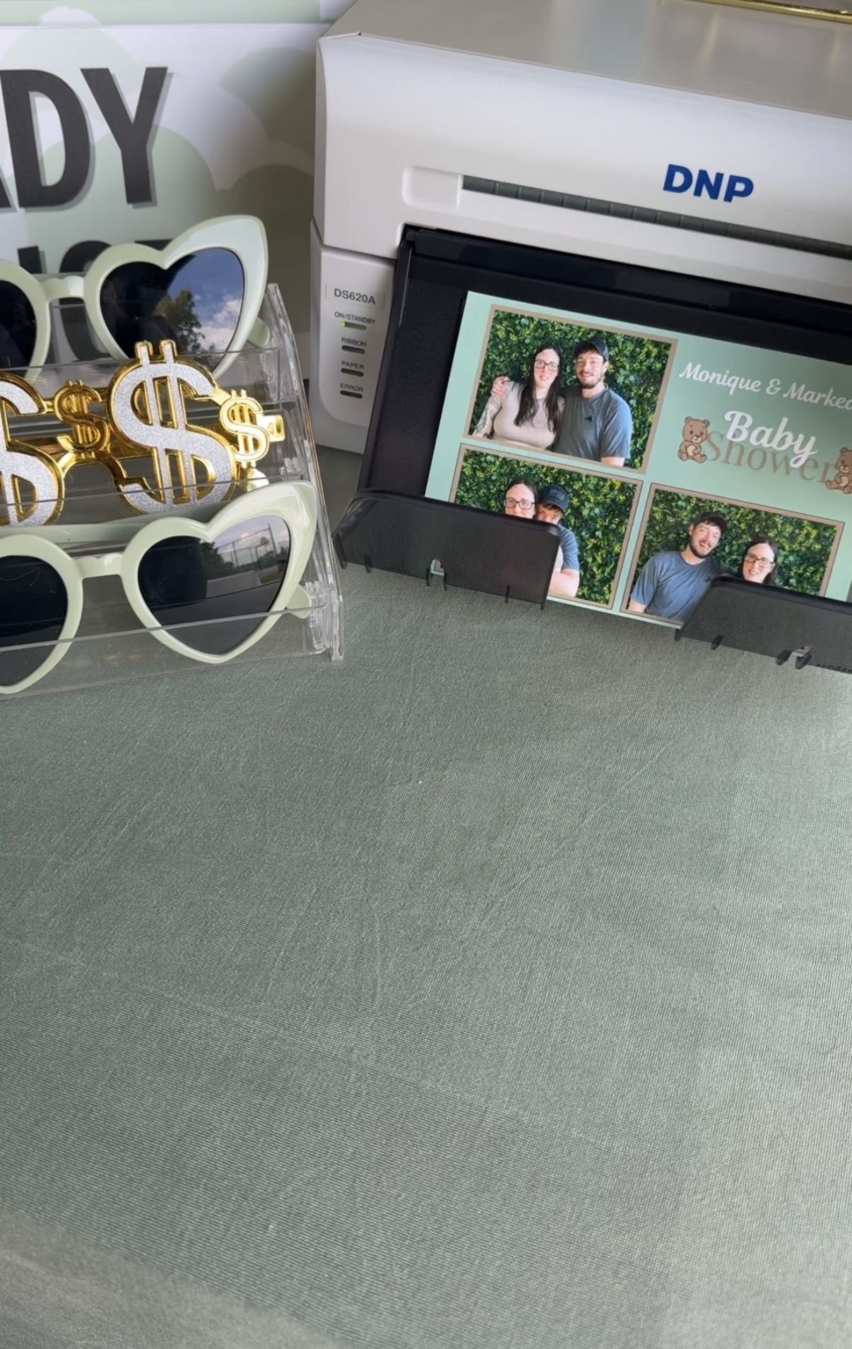Display of photo booth pictures with a man, decorative sunglasses, and a DNP printer in the background.