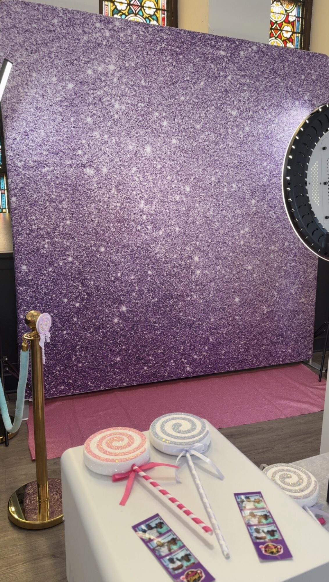 Large purple speckled panel leaning against a wall, with a circular saw partially visible on the right, and a table with lollipops and photos in the foreground.